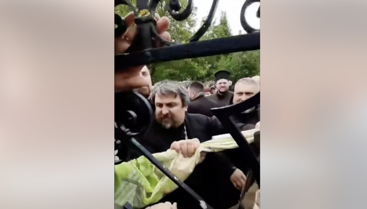 Клірик ПЦУ виламує хвіртку на воротах храму УПЦ в Заставному. Фото: СПЖ