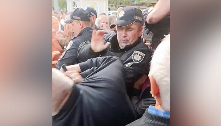 Ο αστυνομικός ασκεί βία στους πιστούς στην Ούστ-Πουτίλα. Φωτογραφία: ΕΟΔ