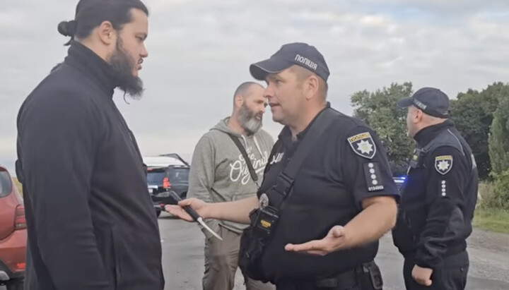 Priest Maksymian speaking with a police officer who initially refused to let the pilgrims’ cars pass. Photo: screenshot from the YouTube channel Children of Mercy