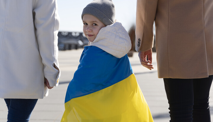 A Ukrainian child holding the national flag during a rally in support of refugees in Europe. Photo: obozrevatel